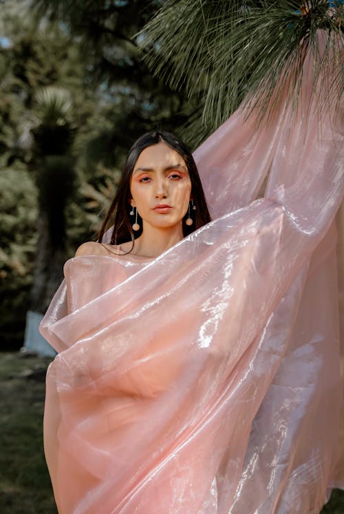 A woman in a pink sari holding a large piece of fabric