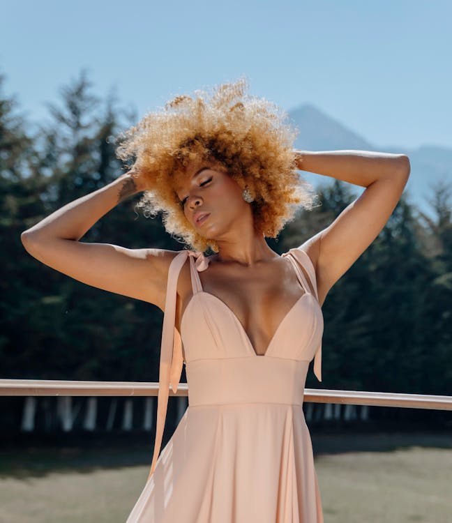 A woman in a peach dress with curly hair
