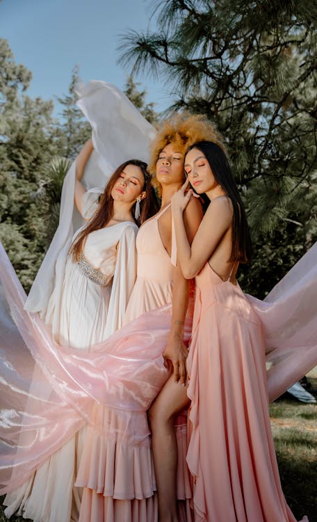 Three women in long dresses pose for a photo