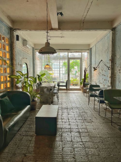 Free Stylish industrial-themed lounge area with plants and natural sunlight. Stock Photo