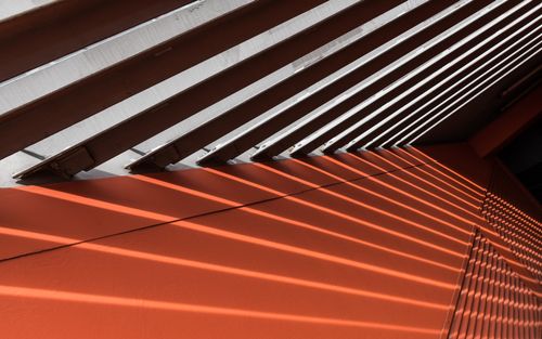 Free Dynamic shadows create an abstract pattern on an orange wall with diagonal lines. Stock Photo