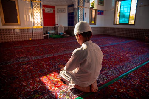A young boy sitting on the floor in a mosque