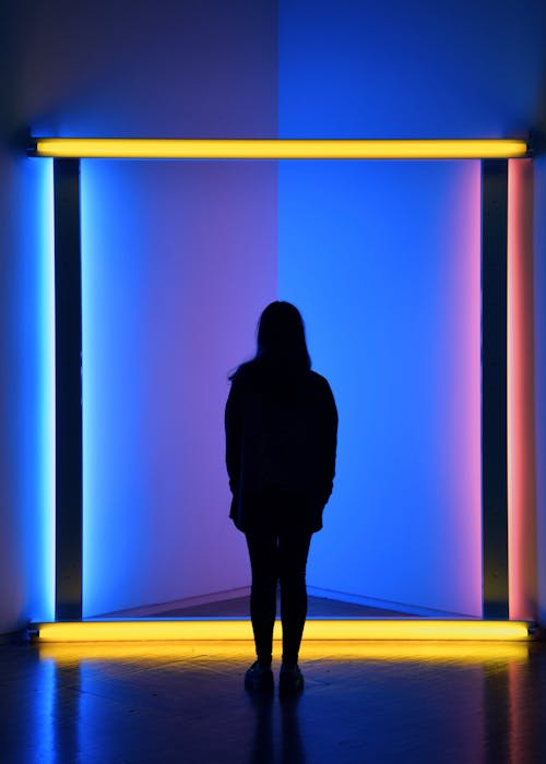 芸術的な背面図ネオン点灯部屋の前に立っている女性のシルエット写真