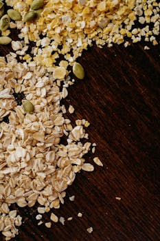 High-angle view of oats, cornmeal, and seeds on a dark wooden table. Perfect for healthy food themes.