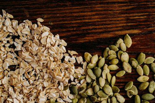 Free A detailed view of oats and pumpkin seeds arranged on a rustic wooden table. Stock Photo