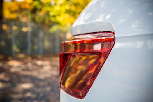 Close-up shot of a modern car's rear light with a blurred autumn background, showcasing sleek design.