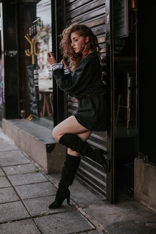 Woman in Black Mini Dress Leaning on Wall