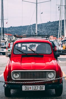 在克罗地亚贝拉卢卡，一辆经典的红色雷诺4汽车停在游艇背景前