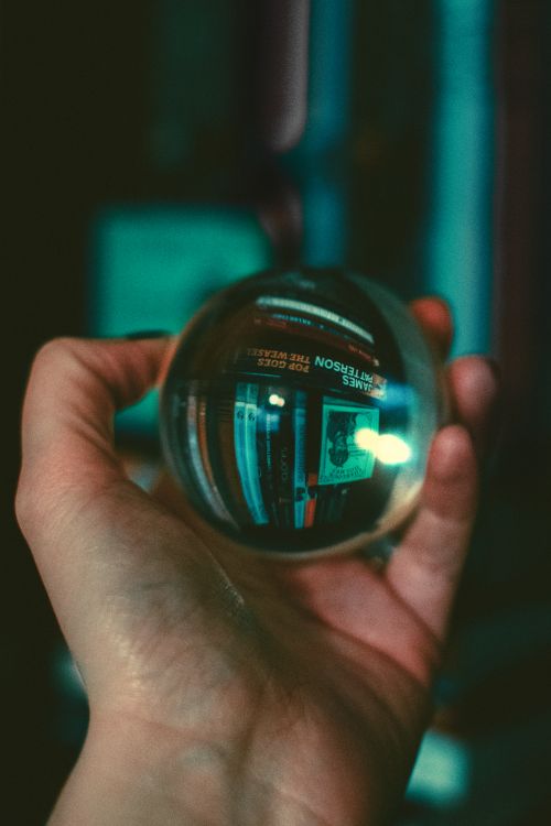 Free A hand holding a lensball reflecting a blurred background indoors. Stock Photo