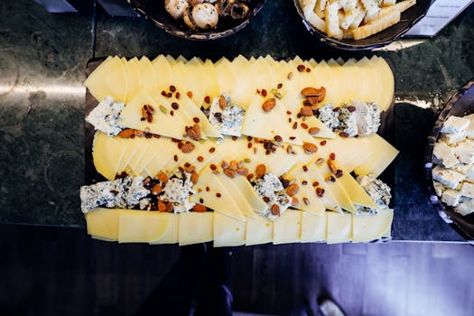 A vibrant cheese platter featuring assorted slices, nuts, and dried fruits on a wooden board.