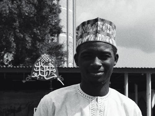 Grayscale Portrait Photo of Smiling Man Standing In Front of Building