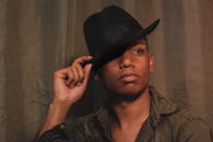 一幅时尚的肖像描绘了一名男子在室内调整黑色软毡帽，营造出温暖的氛围