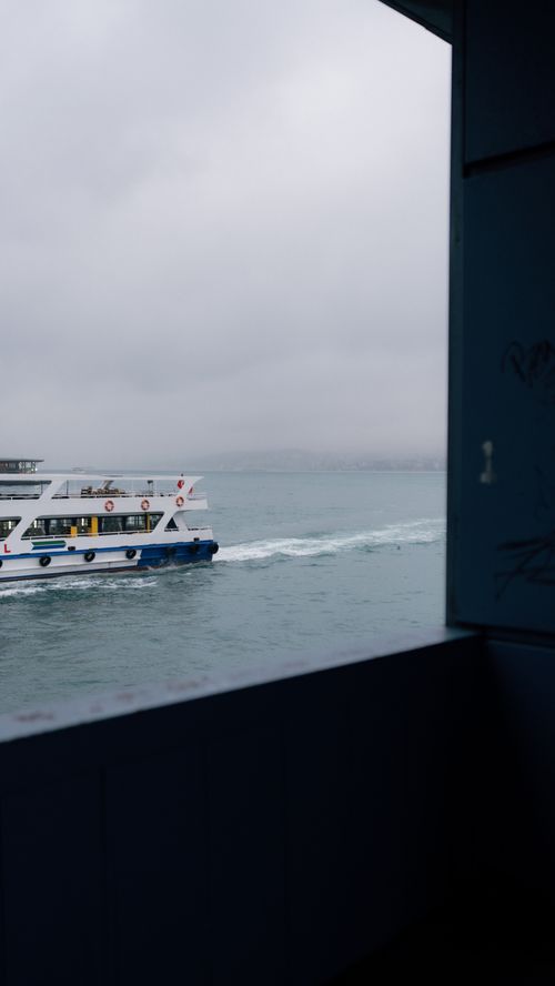 Free A white yacht cruises through a harbor under a cloudy sky, offering a tranquil sea view. Stock Photo