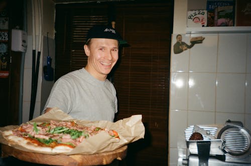 Man Permanent En Glimlachen Terwijl Pizza Vasthoudt