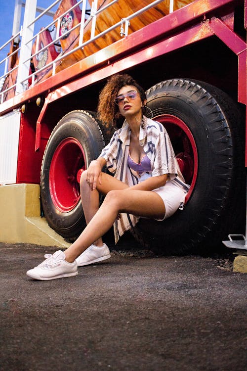 Woman Wearing Purple Bra and White Denim Short Sitting on Tire