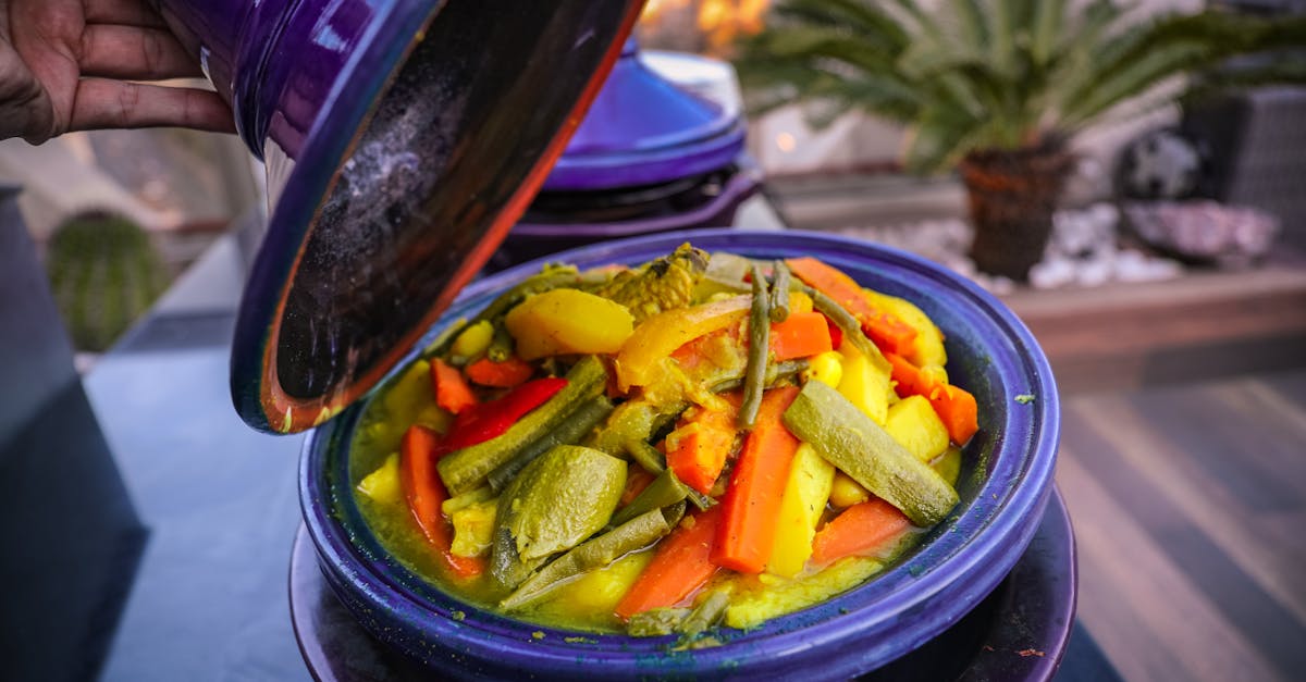Vibrant vegetable tajine served in a traditional purple pot with a variety of fresh ingredients.