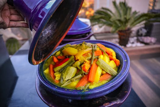 Vibrant vegetable tajine served in a traditional purple pot with a variety of fresh ingredients.