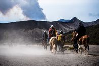 一群冒险者在东爪哇省布罗莫山附近尘土飞扬的风景中骑马