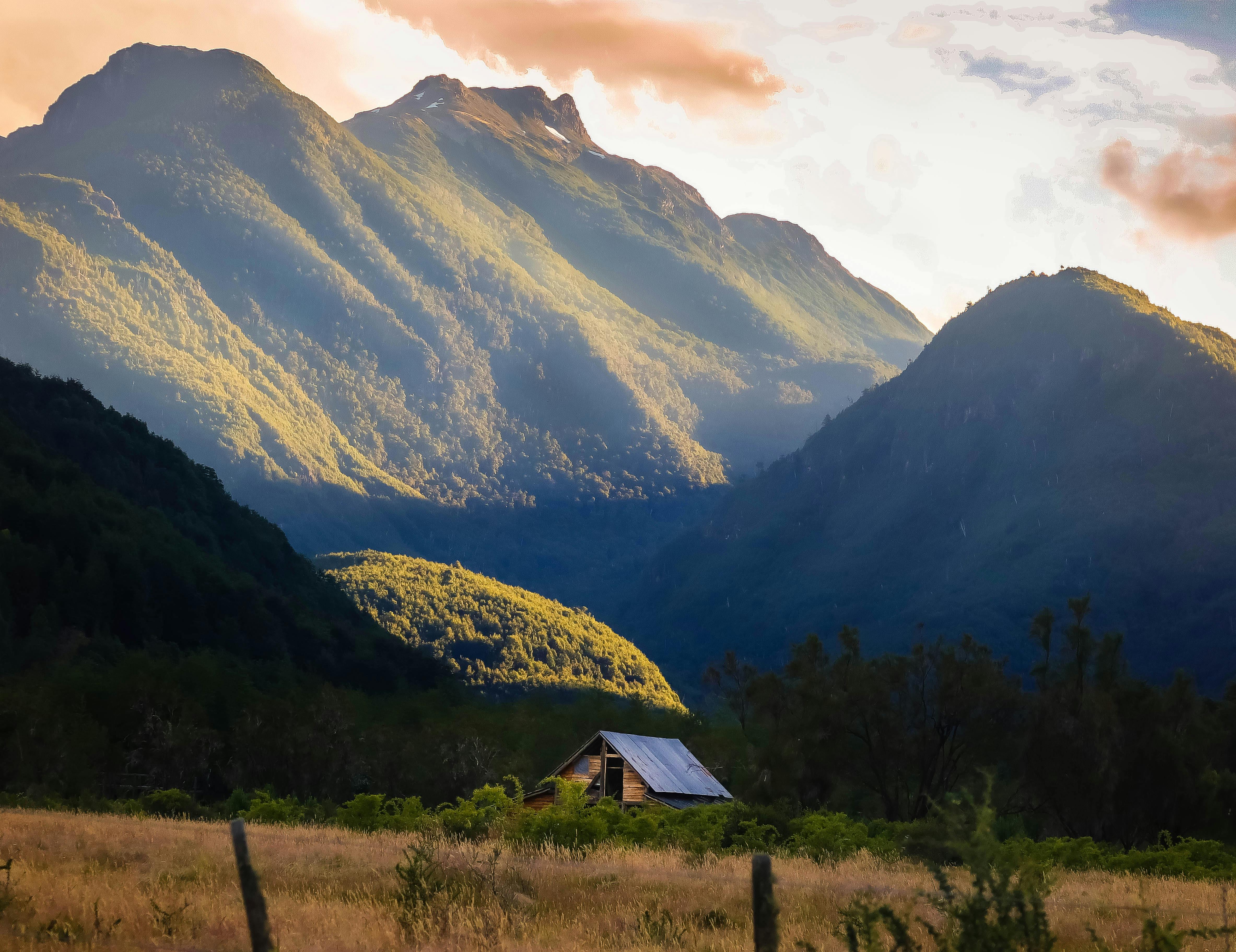 山谷宁静，一栋房屋独立其间，周围青山郁郁葱葱，天空明媚