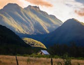 山谷宁静，一栋房屋独立其间，周围青山郁郁葱葱，天空明媚