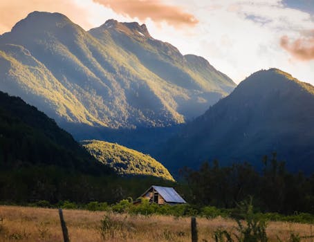 山谷宁静，一栋房屋独立其间，周围青山郁郁葱葱，天空明媚