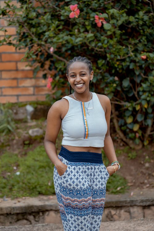 A woman in a crop top and pants smiling