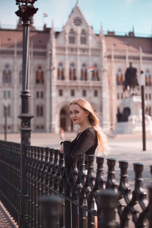 Woman Leaning on Metal Gate