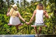 Back View Photo of Couple on Swings Holding Hands