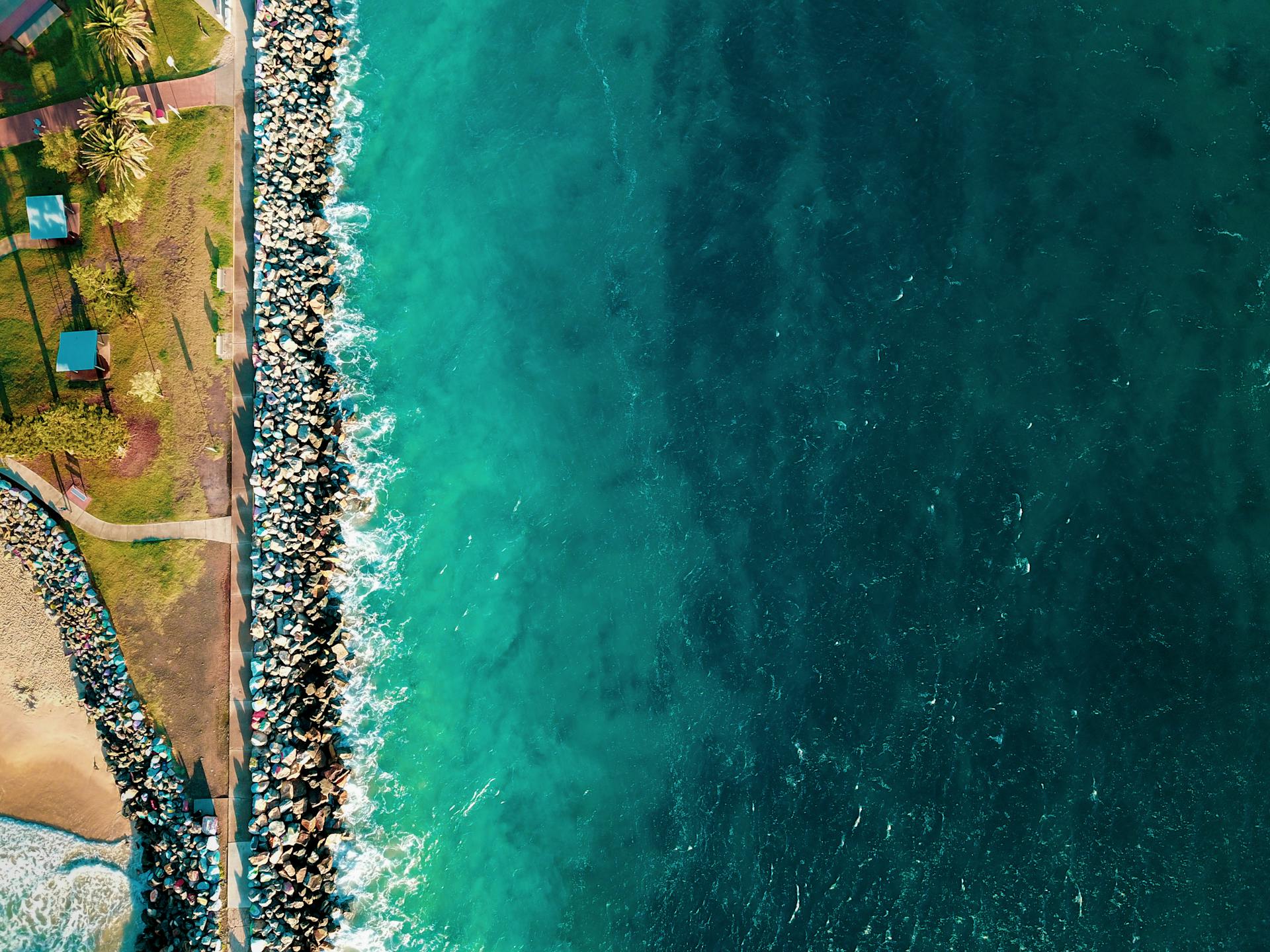 Drone shot capturing the scenic coastline of Port Macquarie with turquoise waters and lush greenery.