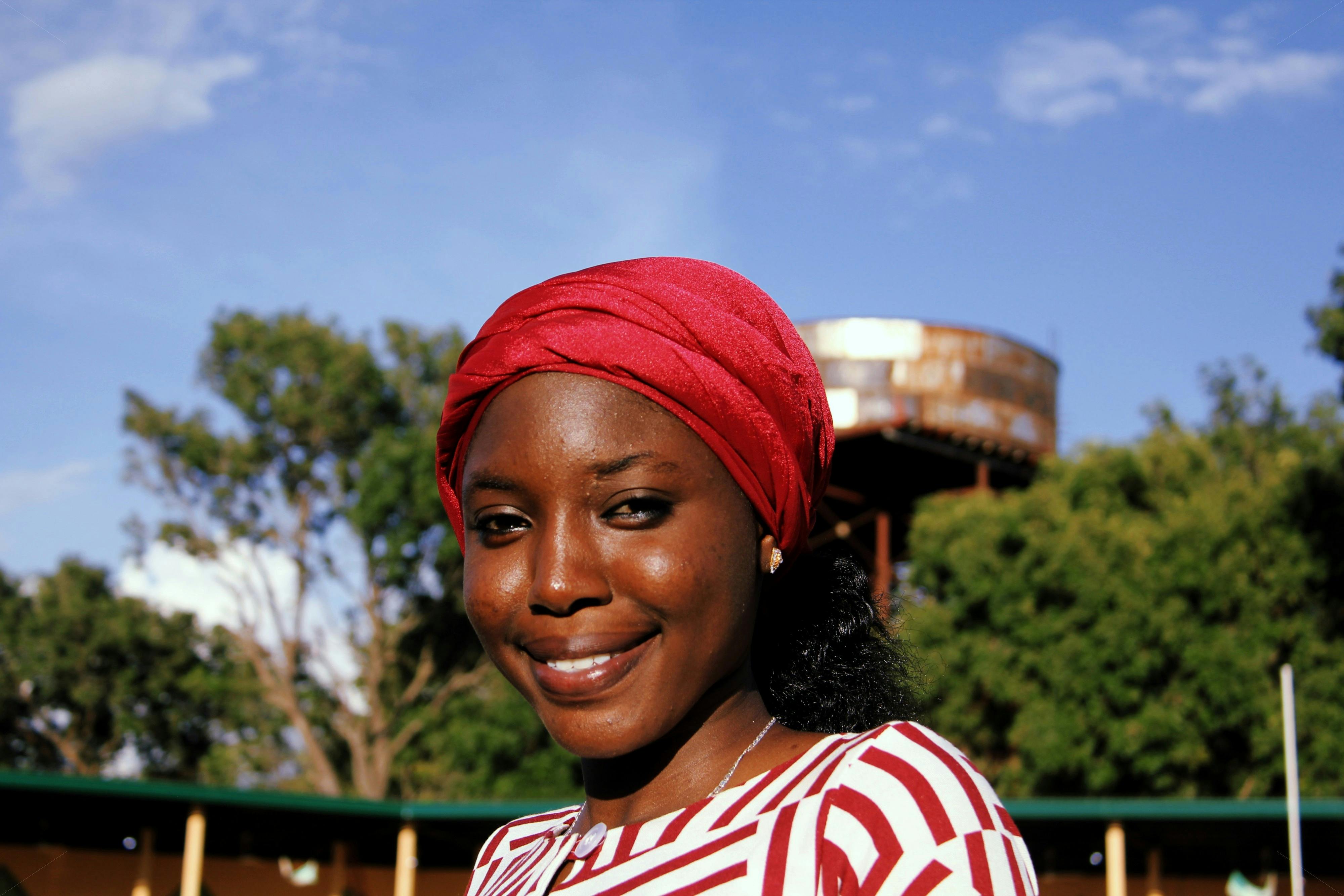 晴朗的天空下，一位戴着红色头巾的快乐女人微笑着