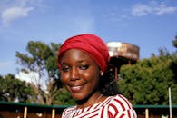 晴朗的天空下，一位戴着红色头巾的快乐女人微笑着