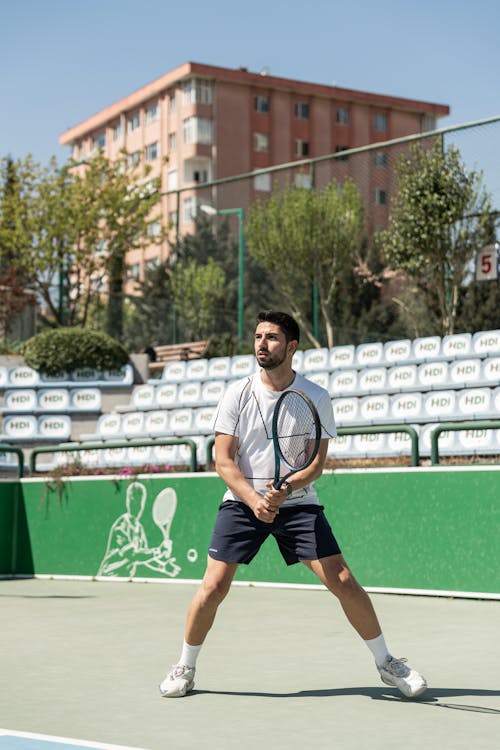 A man in white shorts and a blue shirt is playing tennis