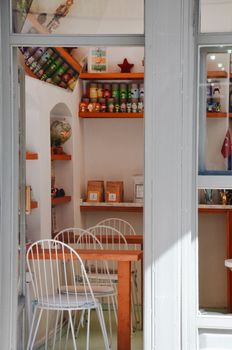 Inviting café interior featuring minimalist design with white chairs, wooden tables, and decorative shelves.