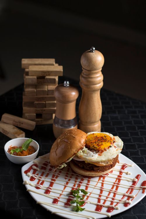 Free Mouth-watering burger with fried egg and gourmet sauce, ideal for lunch or dinner. Stock Photo