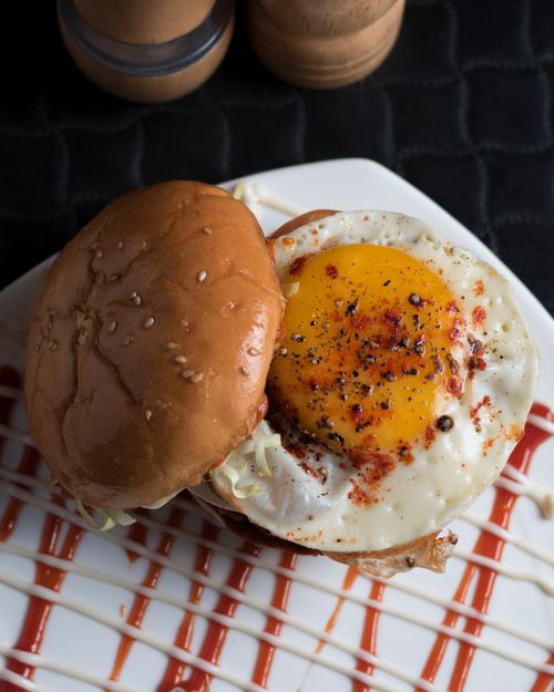 Free Close-up of a tasty egg burger with sesame bun, seasoned to perfection on a plate. Stock Photo