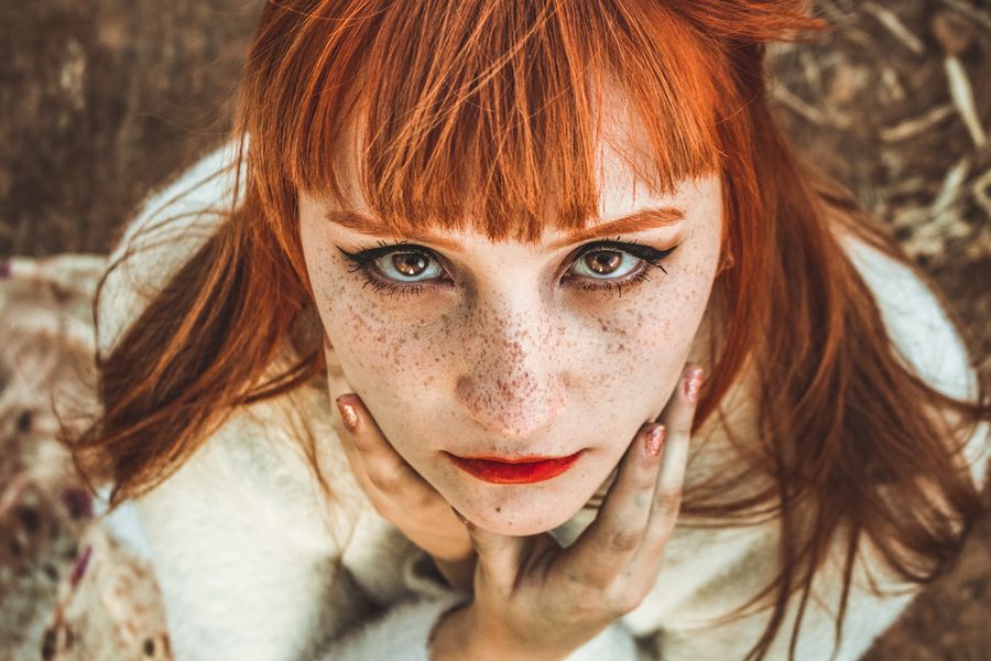 Close beauty portrait of a red-haired woman with freckles and soft natural makeup