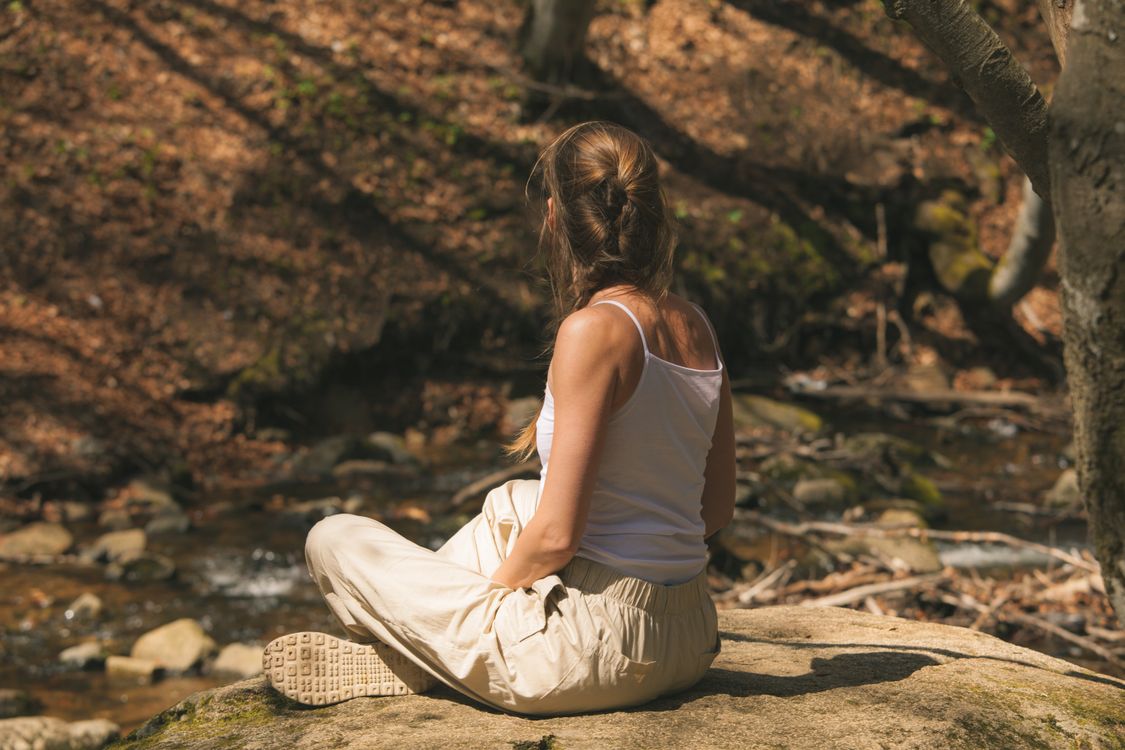 Woman Sitting on a Rock Against Rural Background · Free Stock Photo