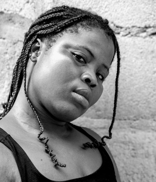 Free Artistic black and white portrait of a woman with dreadlocks posing against a wall. Stock Photo