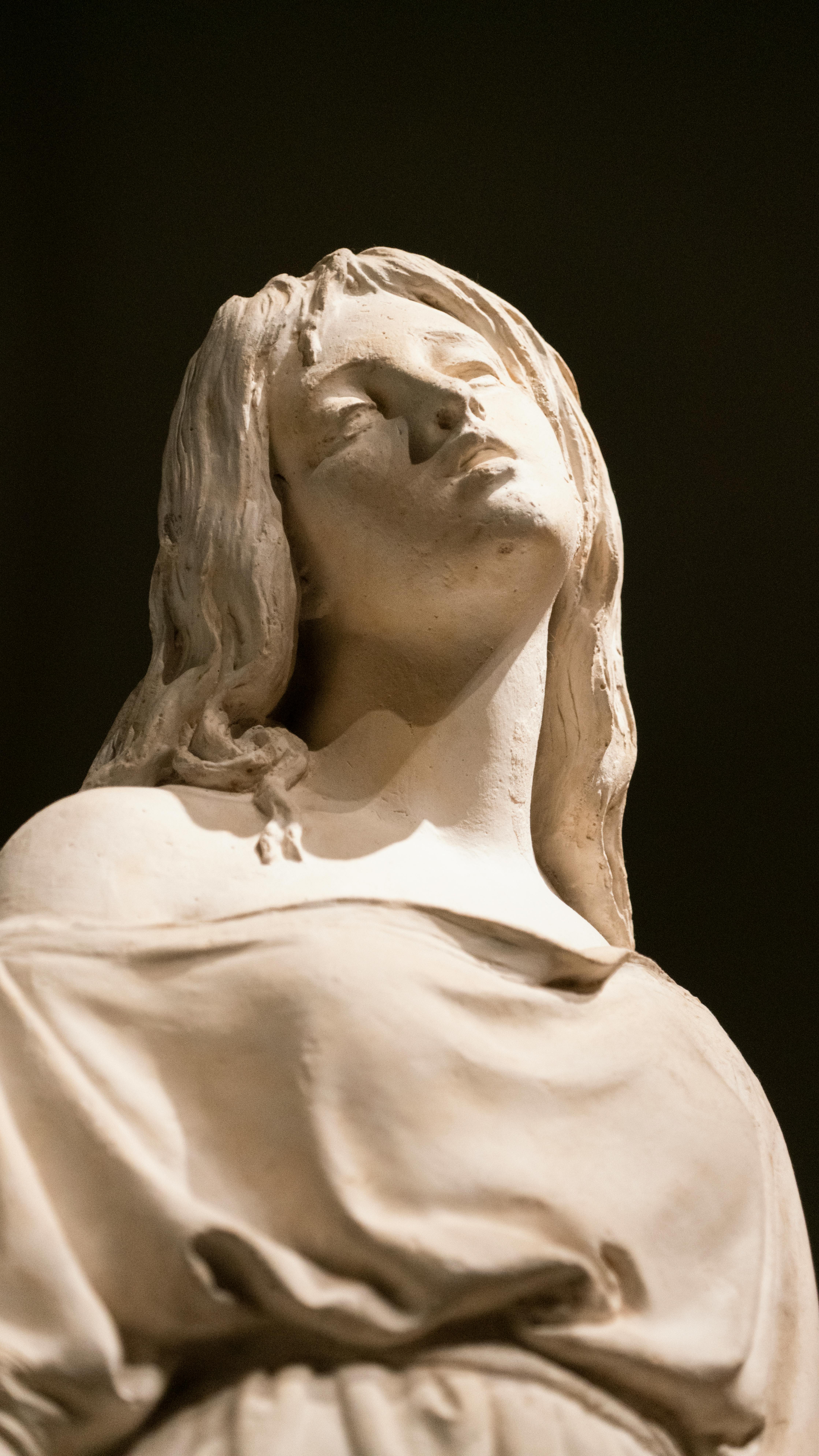 Close-up of a marble statue against a dark background, showcasing its serene elegance.