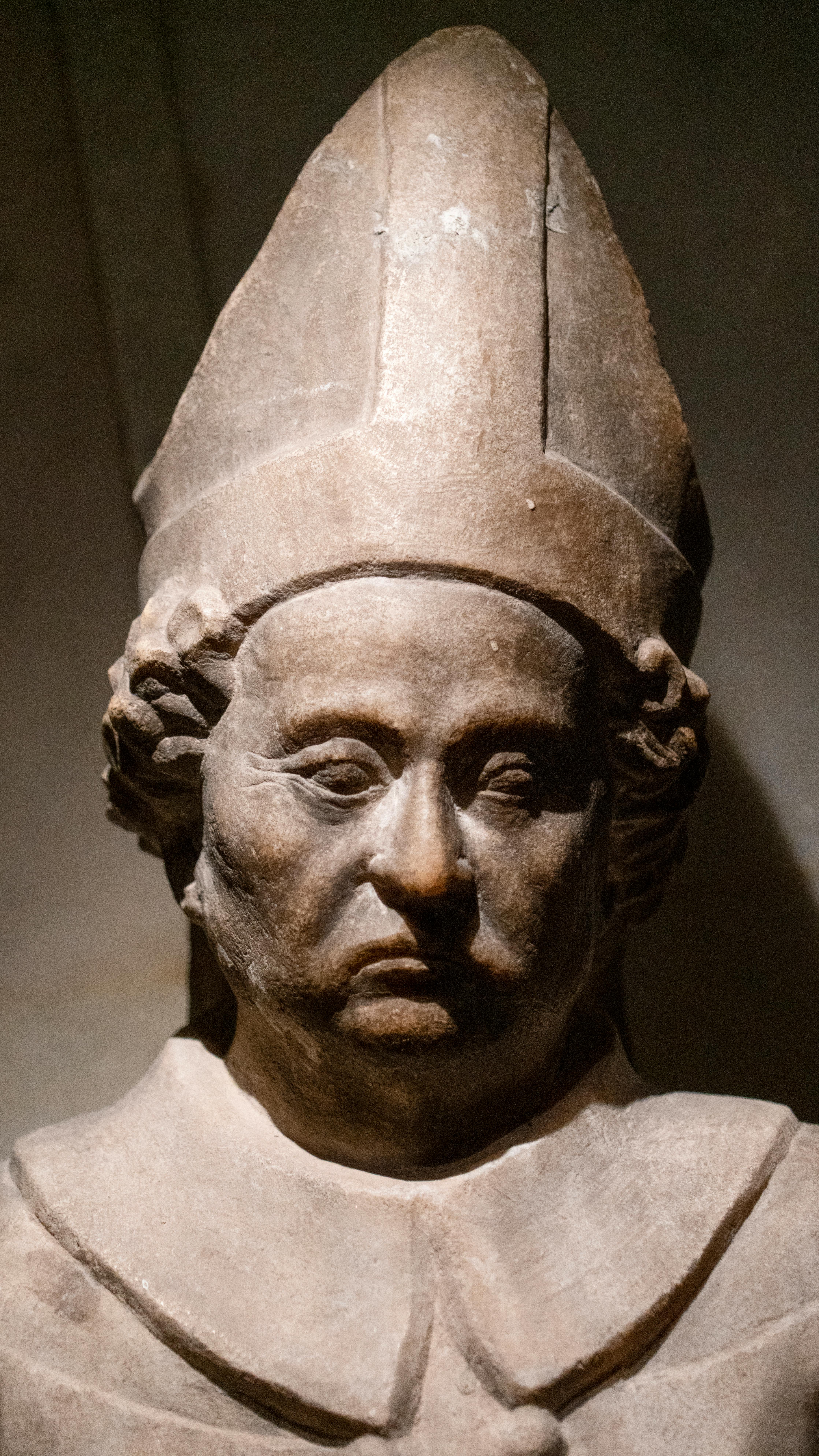 Detailed view of an ancient stone sculpture depicting a religious figure with a mitre.