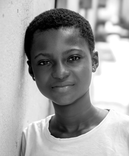 Free A close-up black and white portrait of a young girl leaning against a wall. Stock Photo