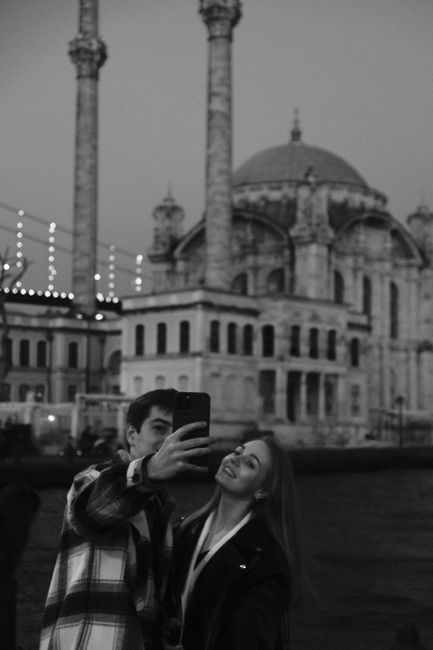 A young couple takes a selfie in front of the iconic Ortaköy Mosque in Istanbul, Turkey.
