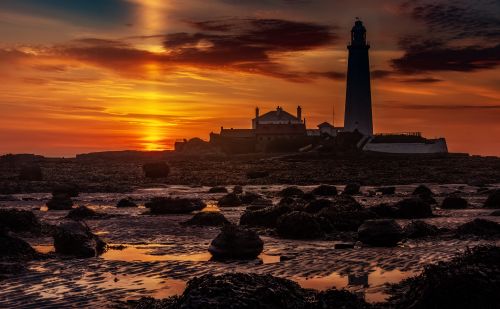 Free Dramatic sunset view of St Mary's Lighthouse, a prominent UK landmark near the sea shore. Stock Photo
