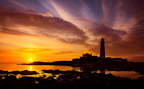 Free A breathtaking sunset view at St Mary's Lighthouse with dramatic skies on the UK coastline. Stock Photo