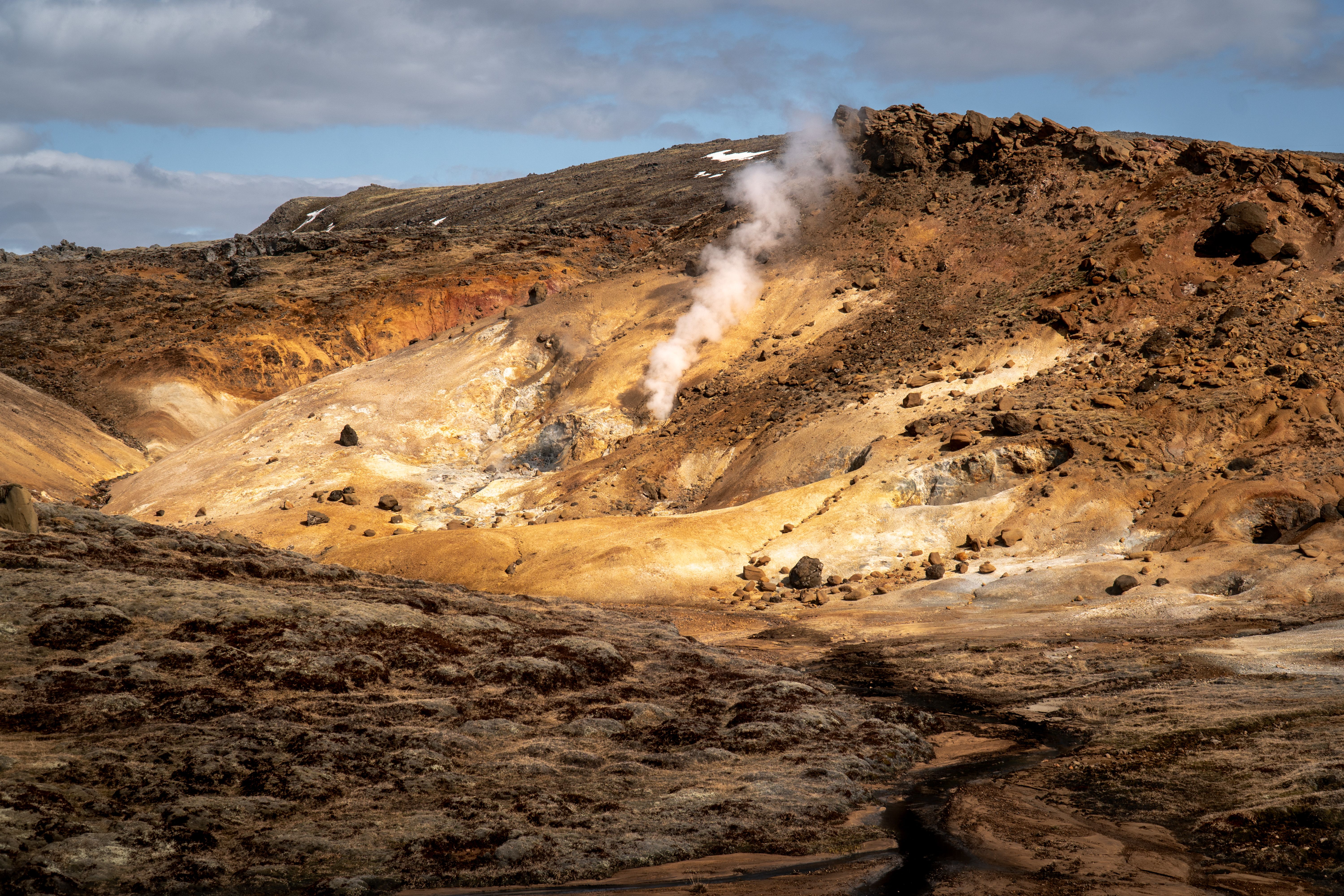 Explore the stunning geothermal terrain of Hveragerði, Iceland, showcasing steaming hot springs and vibrant earth tones.