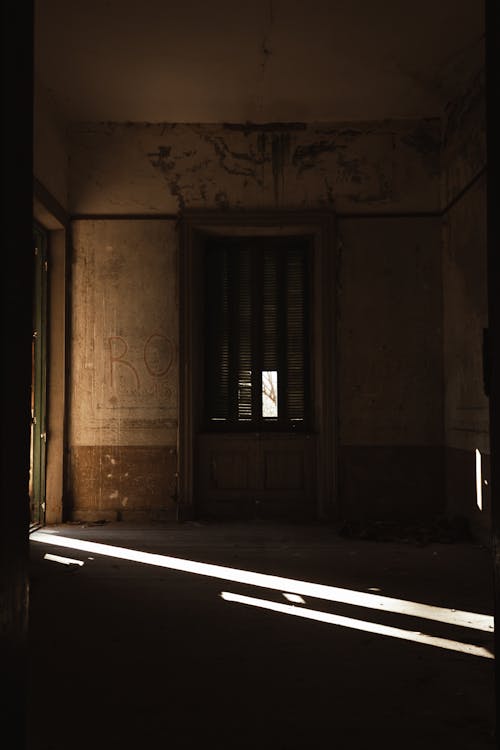 The sun shines through an open door in an old building
