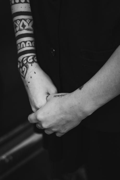 Black and white photo of a person with tattoos on their hands