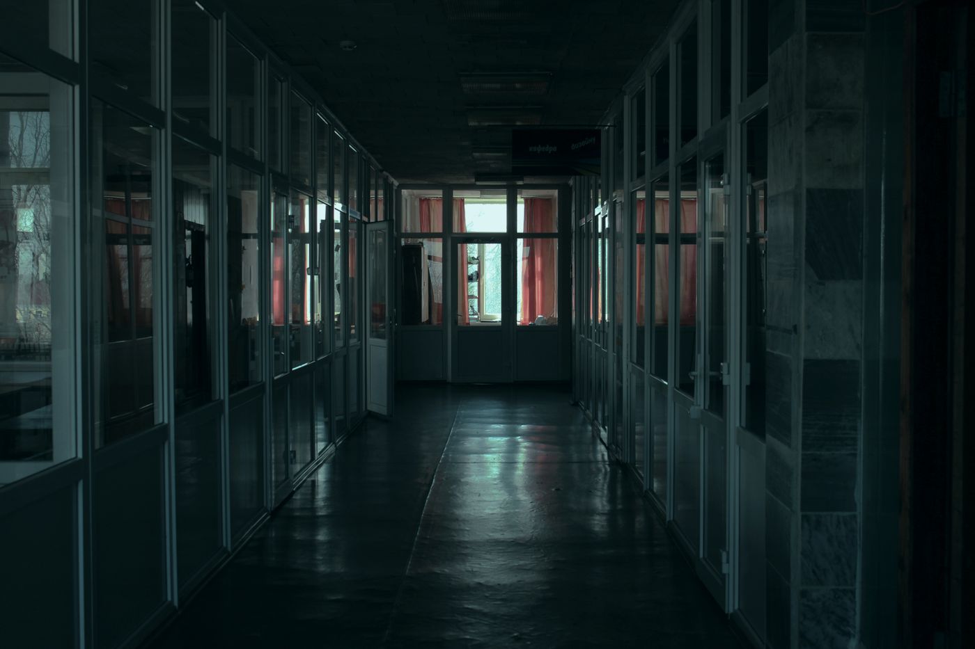 Quiet office corridor with glass partitions and low light