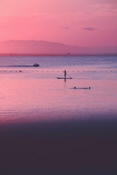 Peaceful paddleboarding on a calm sea during a stunning pink sunset in La Manga, Spain.