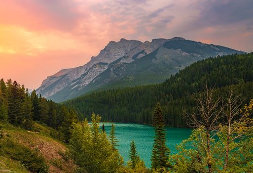 Stunning view of a tranquil mountain lake at sunset with vibrant hues in Banff, Canada.